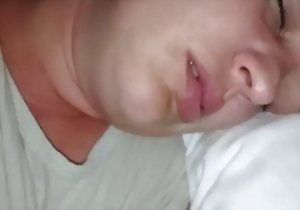 The sleeping lady is feeling his soft penis in front of her face